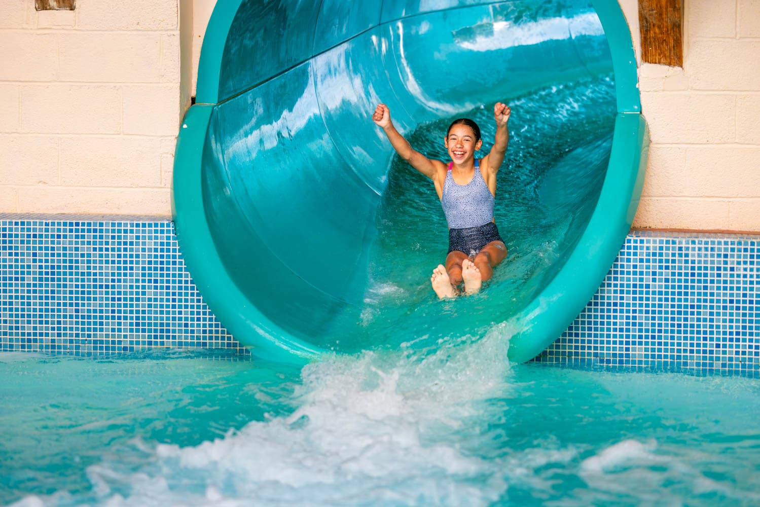Blue Lagoon Waterpark Slide Flume Girl Smiling With Hands In Air