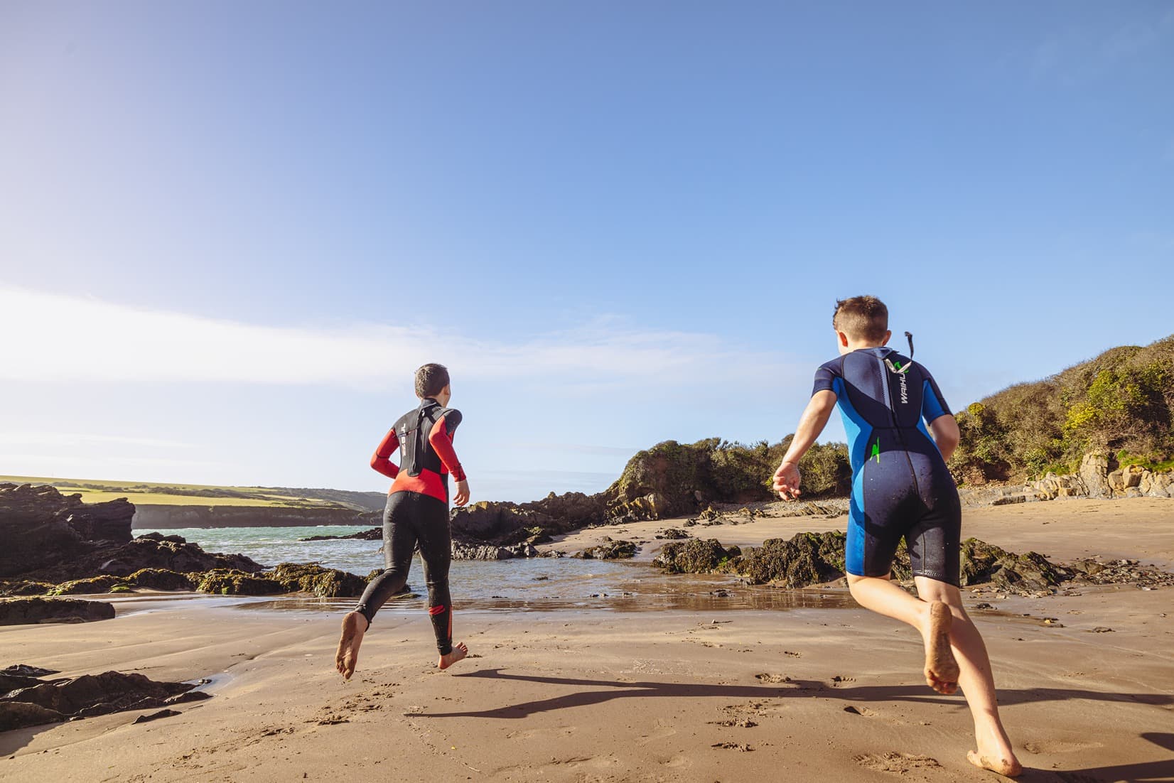 Kids On Beach In Wetsuits